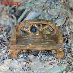 a small wooden bench sitting on the ground in front of a tree trunk and rocks