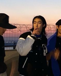 three young men standing next to each other in front of a fence with barbed wire