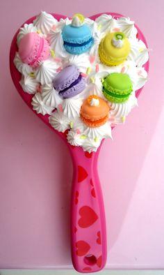 a pink hair brush with cupcakes and macaroons on it's handle