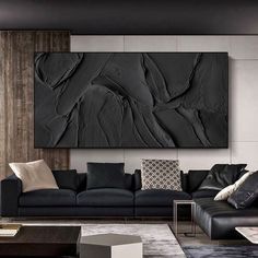 a living room filled with black furniture next to a wall mounted art piece on the wall