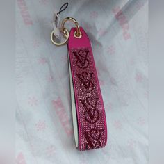 a pink keychain with hearts on it sitting on top of a white sheet