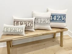 three pillows sitting on top of a wooden bench in front of a wall with numbers