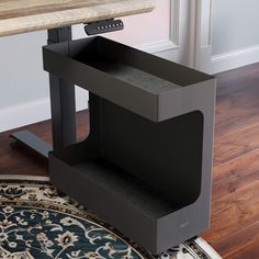 a black computer desk with a wooden table top in front of it and a rug on the floor