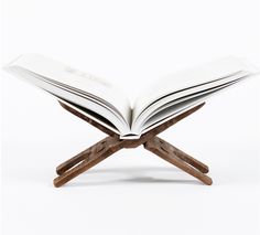 an open book sitting on top of a wooden cross legged stand with two pages spread out