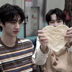 two young men holding up a heart shaped tortilla