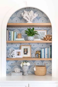 a shelf with books and pictures on it next to a vase filled with white flowers