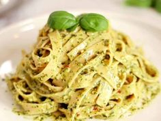 a white plate topped with pasta covered in pesto