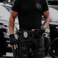 a police officer is standing in front of some parked cars with his hands on his hip