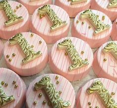 some pink and gold decorated cookies with the letter e on it's top are shown