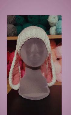 a mannequin head wearing a white knitted bunny ear hat with pink ears