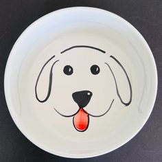 a white bowl with a dog's face painted on the side and tongue sticking out