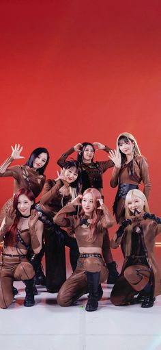 a group of young women standing next to each other in front of a red wall