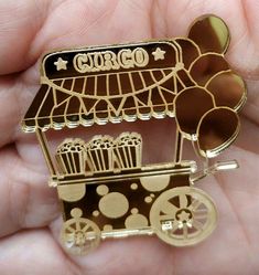 a gold colored brooch depicting a small cart with popcorn