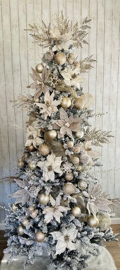 a white christmas tree decorated with gold and silver ornaments