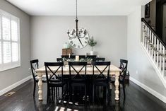 a dining room table with black chairs and a large clock on the wall above it