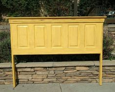 a yellow headboard sitting on top of a stone wall