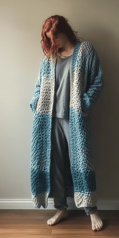 a woman standing in front of a wall wearing a blue and white knitted cardigan