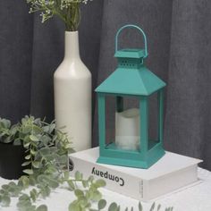 a green lantern sitting on top of a white box next to a vase with flowers