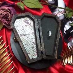 an open jewelry box sitting on top of a table next to flowers and other items