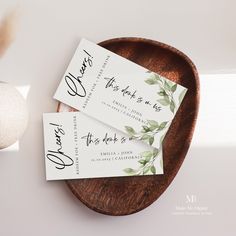 two white business cards sitting on top of a wooden plate next to an easter egg