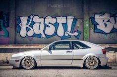 a silver car parked in front of a graffiti covered wall