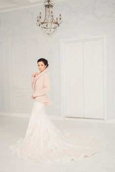 a woman in a wedding dress posing for the camera with a chandelier behind her