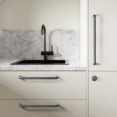 a kitchen with white cabinets and marble counter tops, stainless steel pulls on the handles