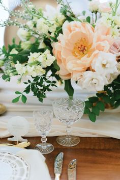 a vase filled with flowers sitting on top of a wooden table next to silverware