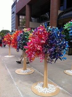 a row of wooden poles with colorful bows on them in front of a tall building