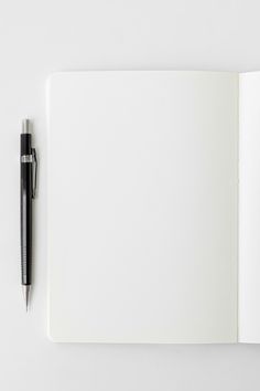 an open notebook with a pen on the top and blank pages in front of it