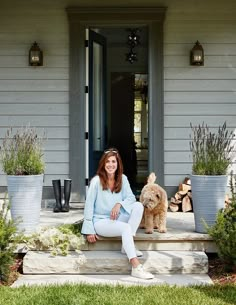 a woman sitting on the steps with her dog and potted plants in front of her