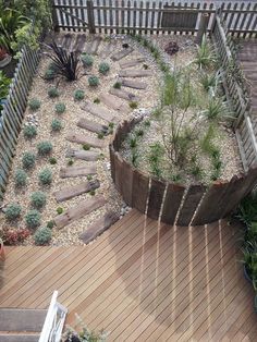 a wooden deck with steps and plants in the center, surrounded by graveled rocks