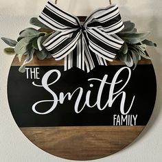 a wooden sign that says the smith family on it with a bow hanging from it's side