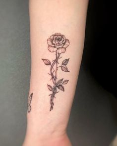 a small rose tattoo on the left inner arm and wrist, with leaves around it