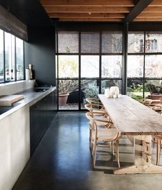 a kitchen with an island counter, sink and stools in front of large windows