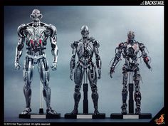 three robots standing next to each other in front of a gray background