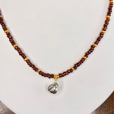 a beaded necklace with a silver and gold charm hanging from it's side