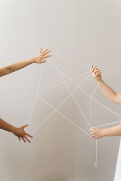 three hands reaching up to string on a wall