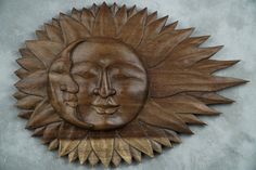 a wooden sun and moon wall hanging on a concrete wall with the face of a smiling man