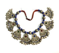 A stunning handmade necklace from Baluchistan kuchi tribe. The necklace is embellished with nine alloy beads and blue glass beads. Eight beautifully designed pendants are precisely positioned between each pair of alloy beads, with thirteen dangles suspended from each pendant. Every aspect of the necklace has been carefully crafted to represent the tribe's rich cultural heritage. The necklace is in good condition, with minor signs of wear consistent with its age . Traditional Dangle Jewelry With Bead Caps, Traditional Blue Jewelry With Bead Caps, Bohemian Dangling Beads For Celebrations, Traditional Blue Beads With Silver Details, Traditional Large Beaded Dangle Necklaces, Traditional Turquoise Necklace With Dangling Beads, Traditional Adjustable Necklace With Bead Caps, Silver Bohemian Beaded Necklace With Bead Caps, Silver Bohemian Beaded Necklaces With Bead Caps