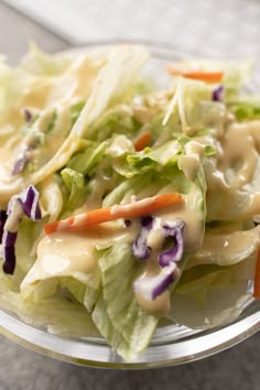 a salad in a glass bowl with dressing on top