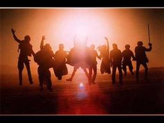 a group of people jumping in the air at sunset