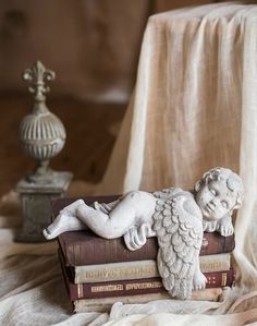 a statue of an angel laying on top of some books