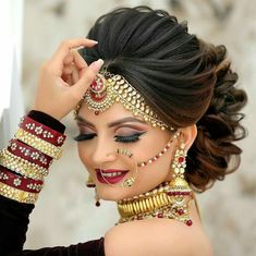 a woman with dark hair and gold jewelry on her face, wearing an elaborate head piece