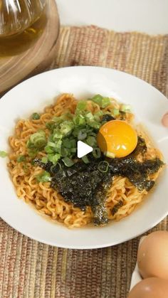 a bowl of noodles with an egg on top and greens in the middle, sitting on a place mat