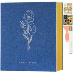 a blue notebook with a flower drawn on the cover and pencils next to it