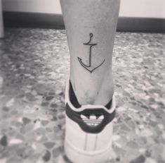 a small anchor tattoo on the leg of a person's foot in black and white