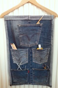 an old pair of jeans hanging on a wooden hanger with scissors and pencils in it