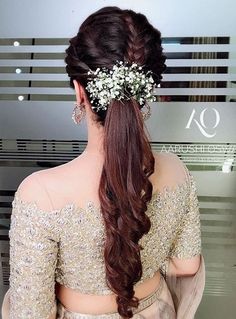 a woman with long hair wearing a flower in her hair, looking back at the camera