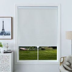 a living room with white walls and an open window that has the eiffel tower in the background